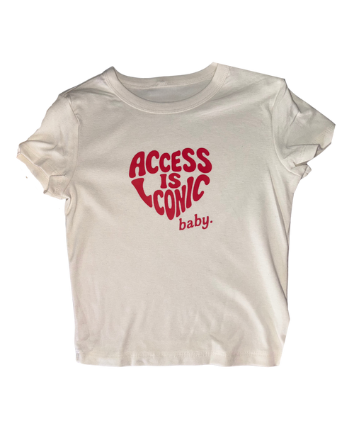 A close-up photo of  wearing a crop top stretchy t-shirt with the "Access Is Iconic Baby" design in red. It's in the center of the tshirt. 