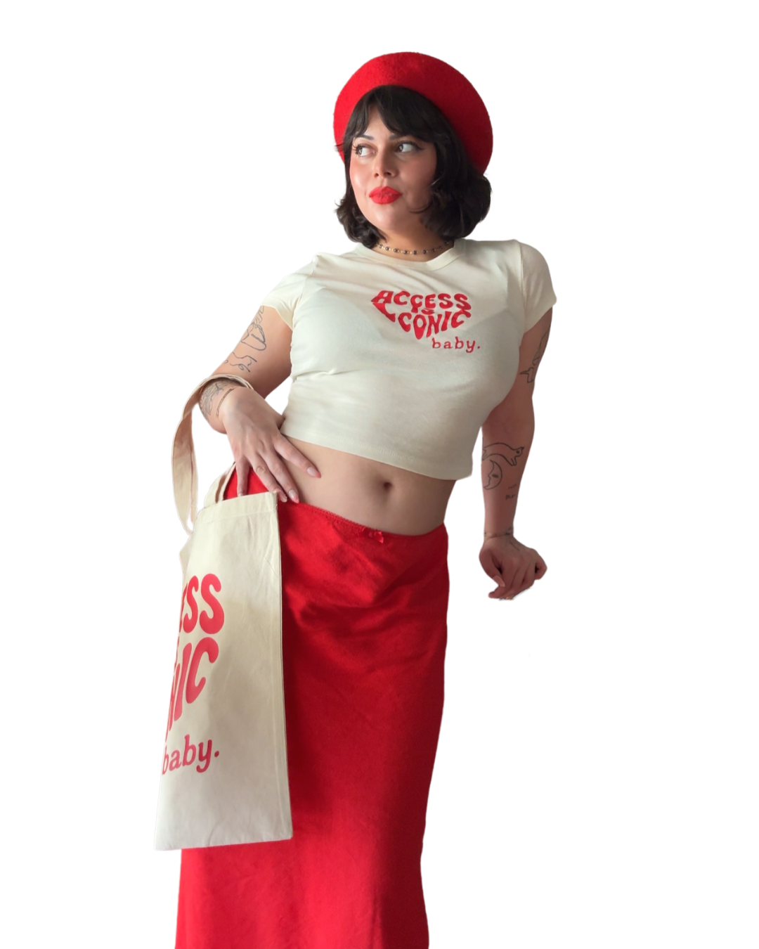 A photo of a woman wearing a regular length cotton t-shirt with the "Access Is Iconic Baby" design in red. It's in the center of the tshirt. She's wearing it with a matching tote, red beret, and red skirt.