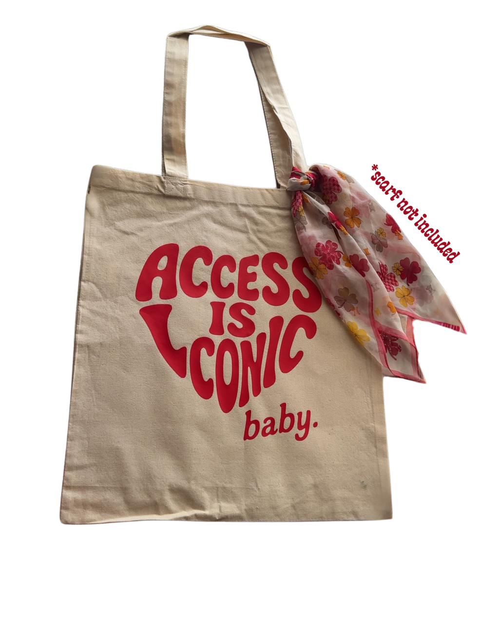 A  photo of a cotton tote with the "Access Is Iconic Baby" design in red. It's in the center of the tote. There's a red silk scarf (not included) tied around the strap.