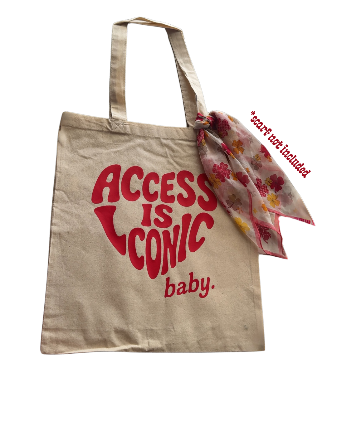 A  photo of a cotton tote with the "Access Is Iconic Baby" design in red. It's in the center of the tote. There's a red silk scarf (not included) tied around the strap.