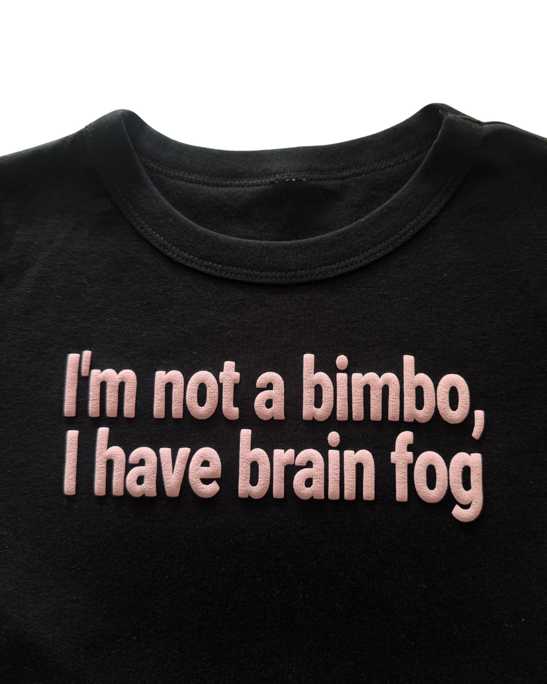 Black shirt with pink text "I'm not a bimbo, I have brain fog" on a white background. The text is wrinkly, resembling a brain. 