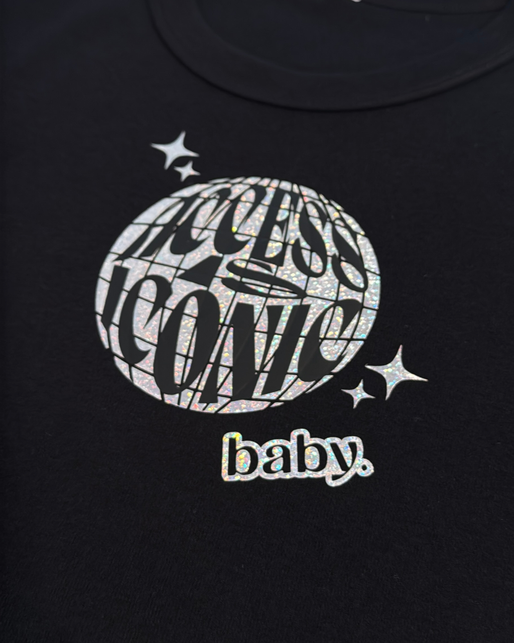 close up black crop top with holographic "access is iconic baby" disco ball graphic design on it
