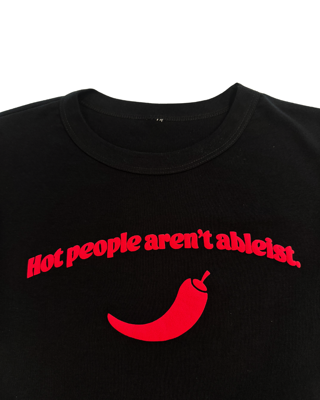 close up of black crop top with red text and a red pepper graphic that says "hot people arent ableist" on a white background. Gender neutral version