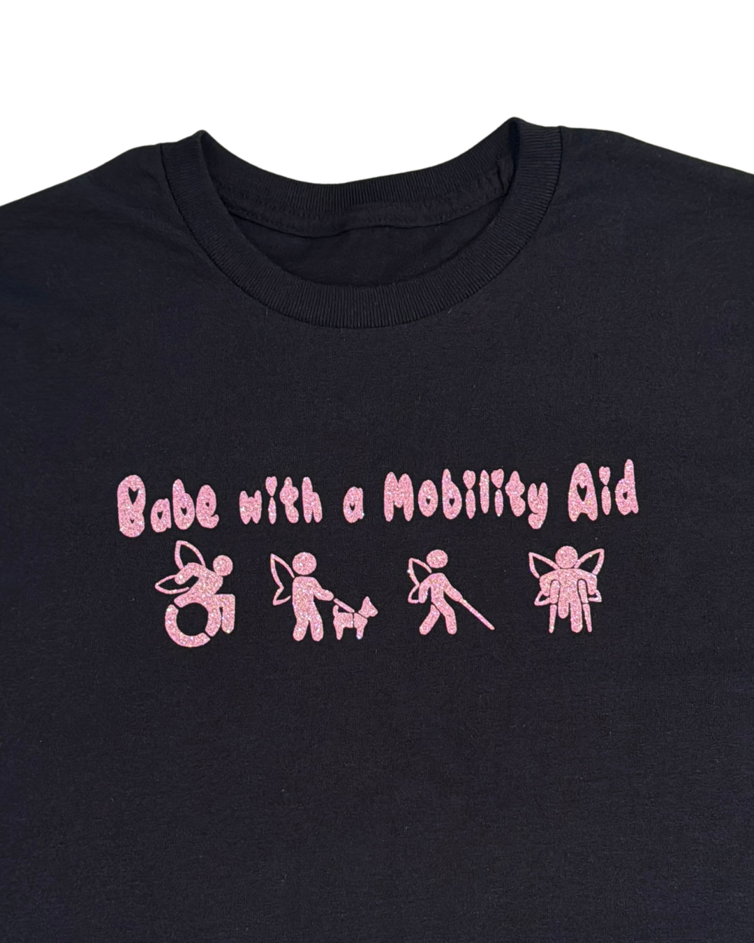close up of back t-shirt with pink glitter text that says "Babe with a mobility aid" in bubble letter typography and disability symbols on a white background