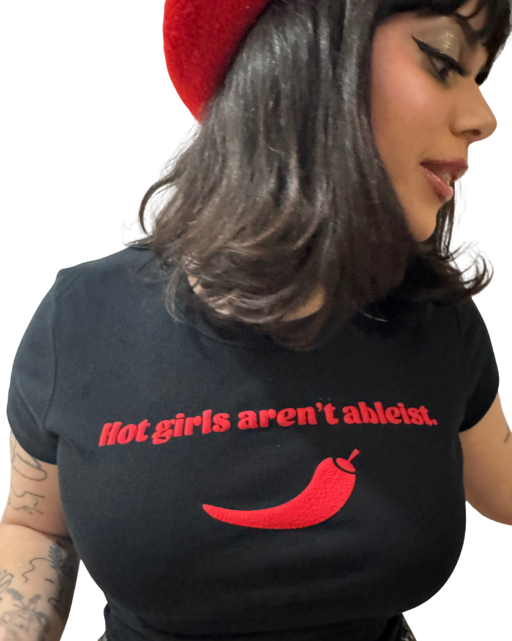Person wearing a black t-shirt with red text "hot girls arent ableist" and a red chili pepper graphic, with a red beret
